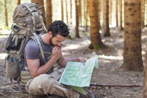 Beard Man with Backpack and map searching directions in wilderness area