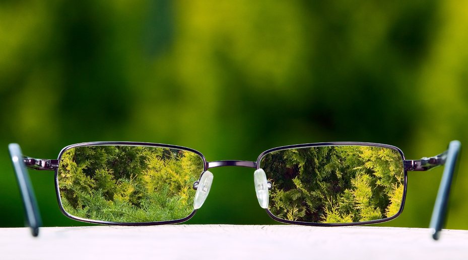 Eyeglasses placed on table with green nature background