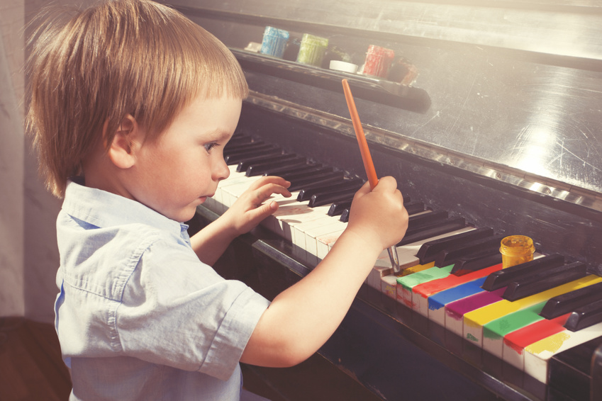 Young boy painting piano keys with brush.
